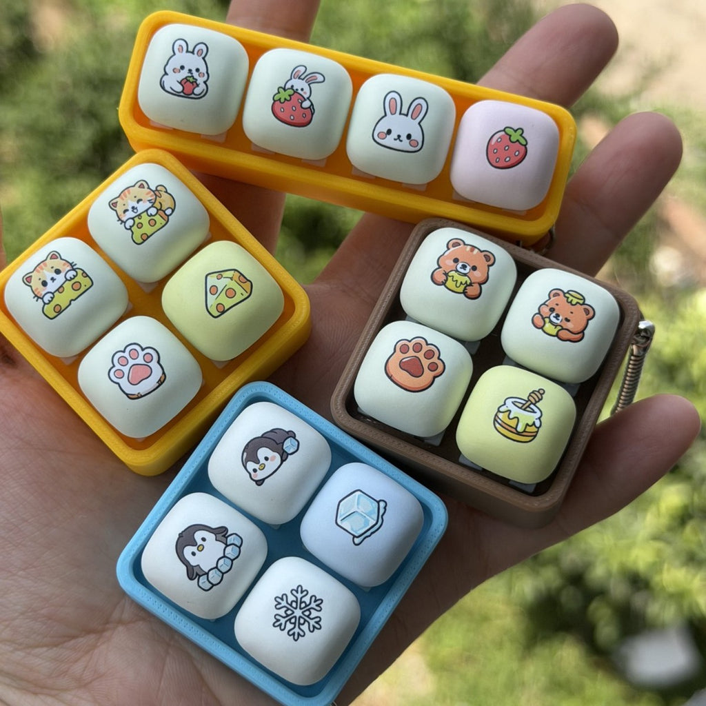 Four animal tray 4-key keycap clicker keychains held in a hand