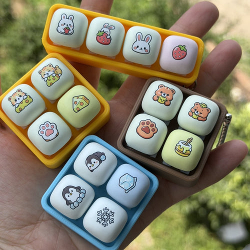 Four animal tray 4-key keycap clicker keychains held in a hand