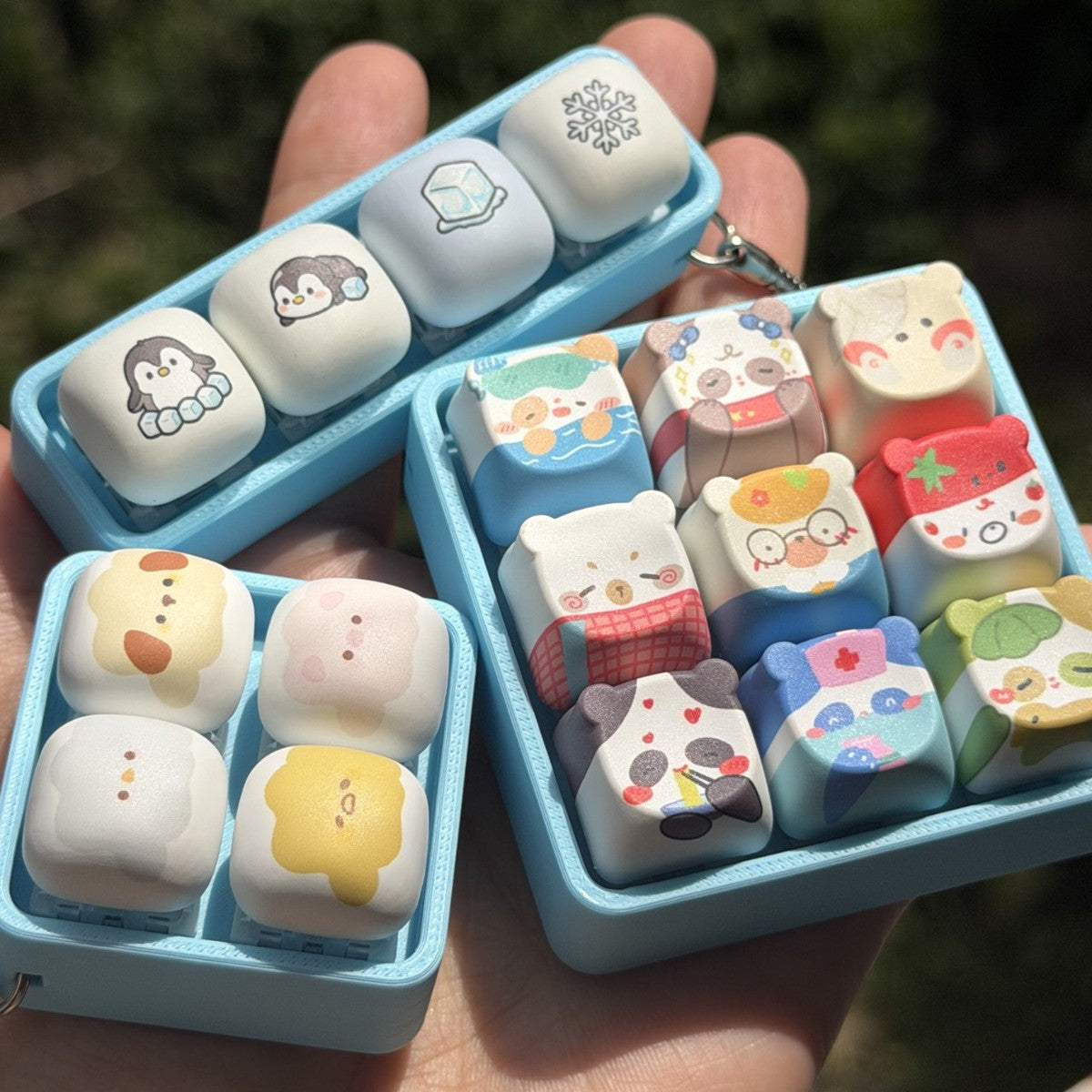 Hand holding blue-frame cartoon animal keycap clicker keychains