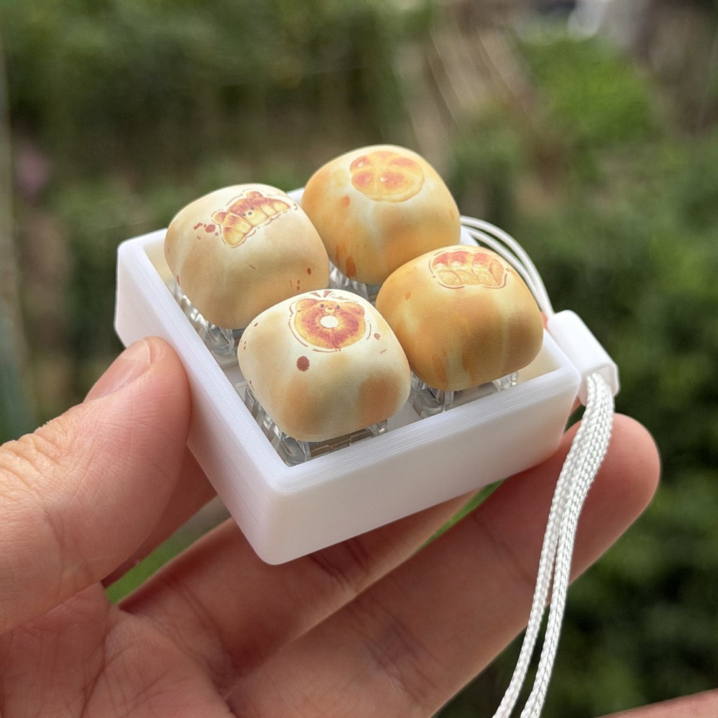 Bread collection 4-key keycap clicker with a strap held at an angle
