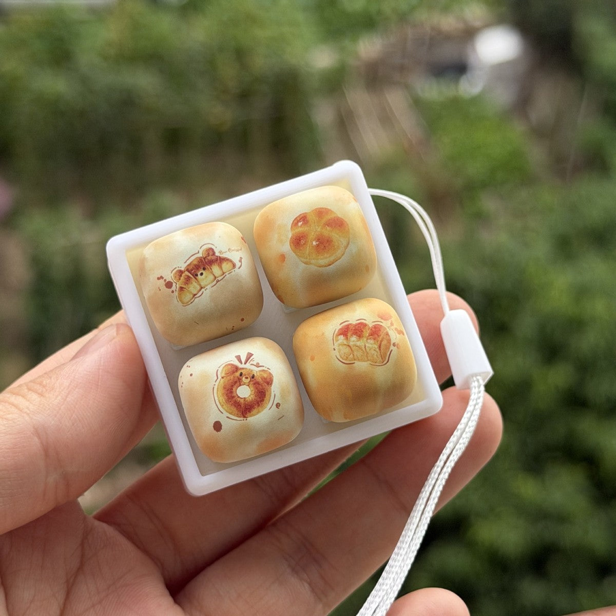 Hand holding the bread collection keycap clicker with a strap
