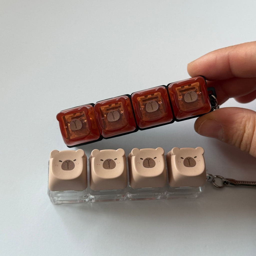 Hand holding capybara 4-key keycap clicker keychains