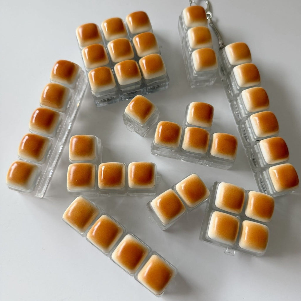Golden bread keycap clicker keychains in 1 to 9-key layouts laid out together