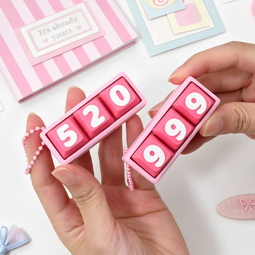 Hand holding pink 520 and 999 keycap clicker keychains with pink ball chains
