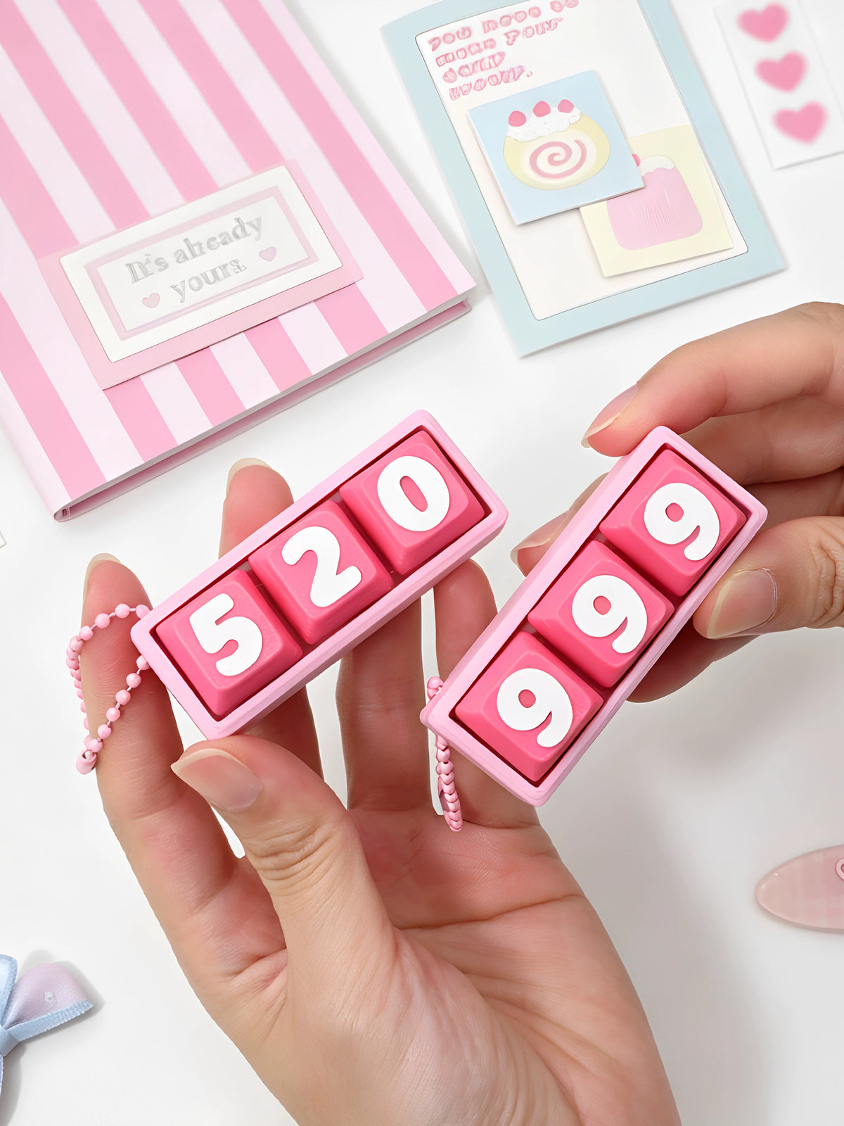 Close-up of pink 999 and 520 3-key clicker keychains in hand