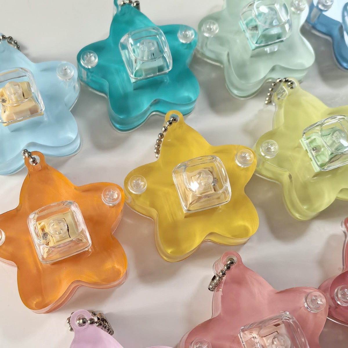 Close-up of translucent star keycap clicker keychains in yellow, orange, pink and blue