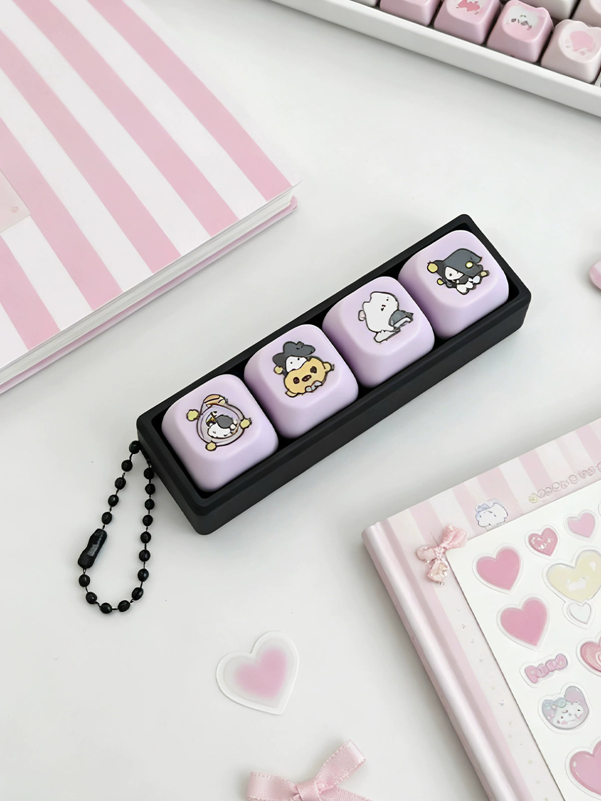Magic cat 4-key clicker keychain with black ball chain next to pink stationery