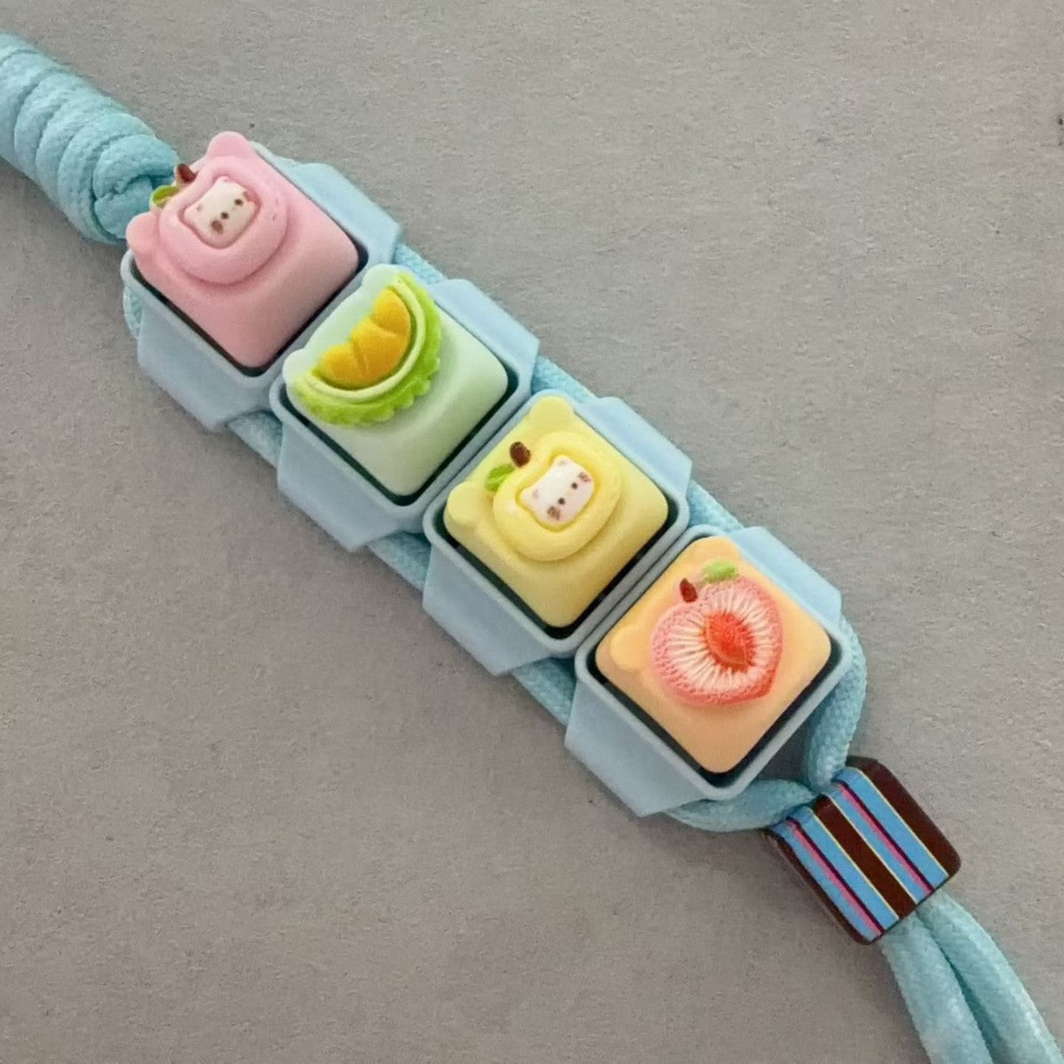 Assembled modular keycap clicker keychain on a teal cord