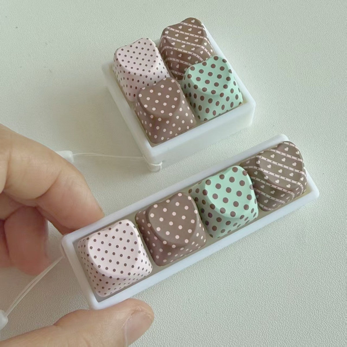 Hand holding the in-line polka-dot keycap clicker keychain