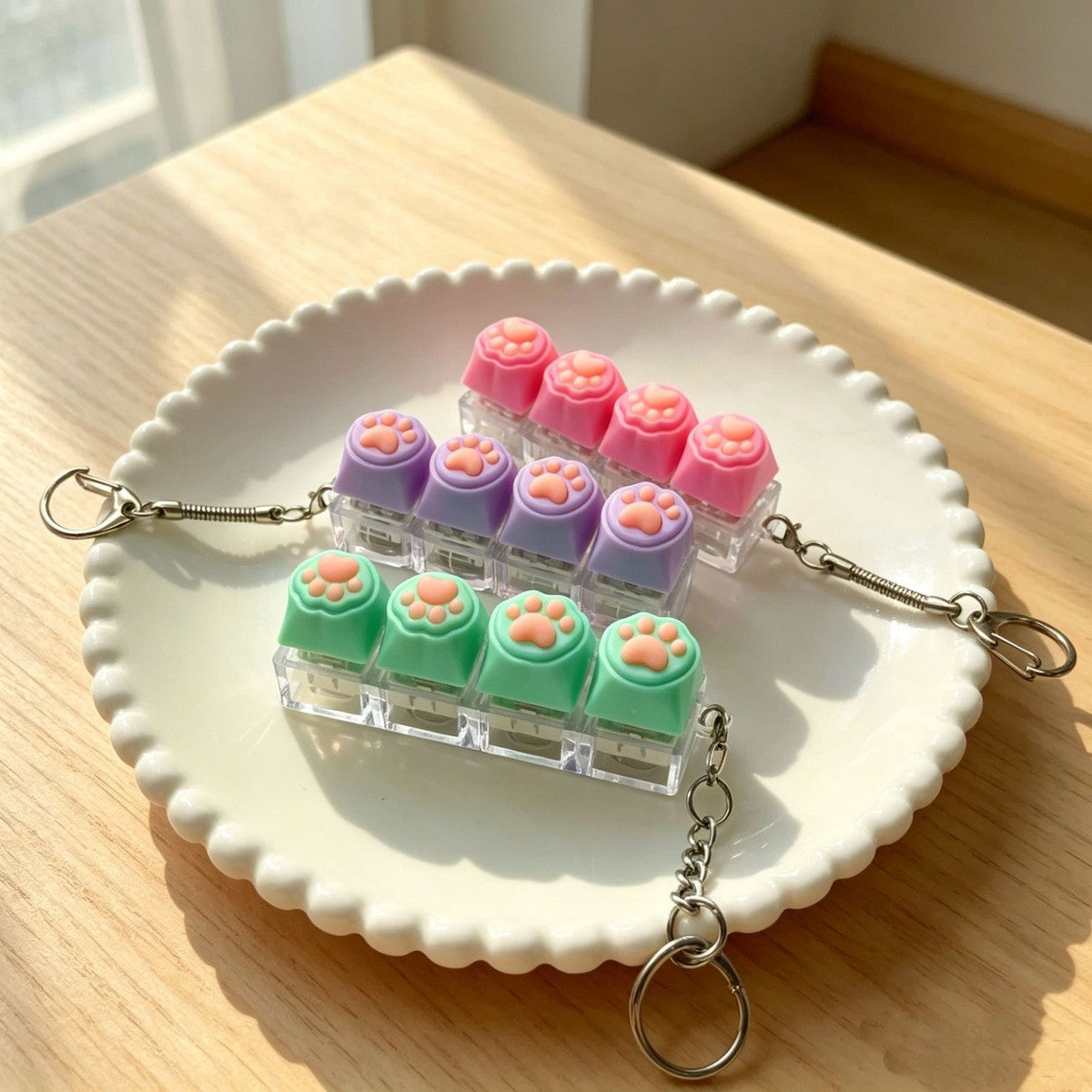 Silicone cat paw 4-key keycap clicker keychains in pink, purple and green on a plate