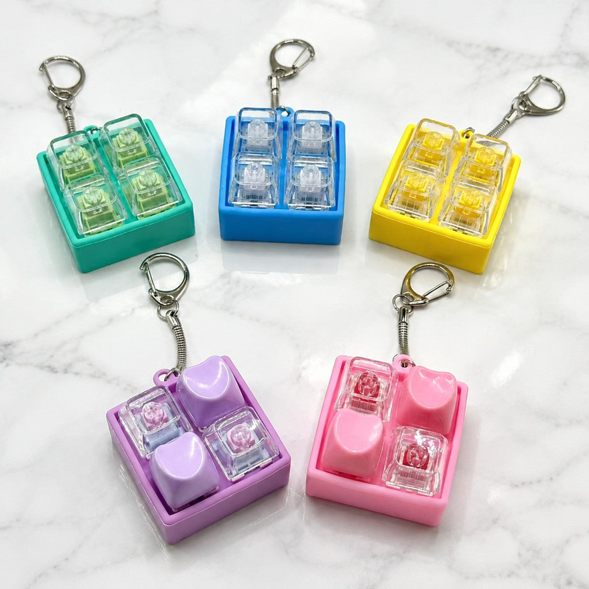 Five coloured 2x2 four-key switch block keychains on a marble surface