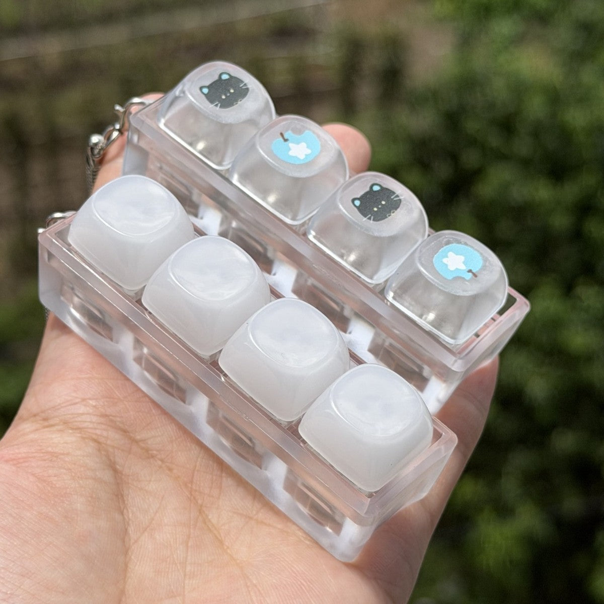 Frosted white 4-key keycap clicker keychain in a transparent frame
